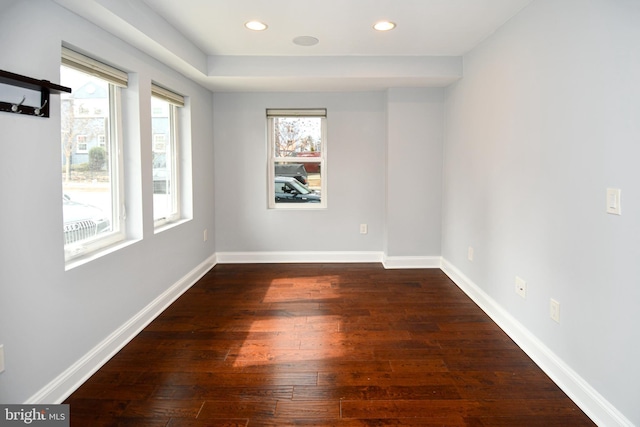 unfurnished room featuring a healthy amount of sunlight, dark wood-style flooring, and baseboards