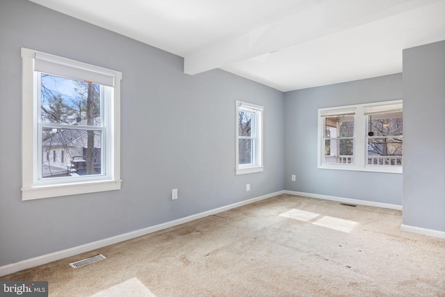 unfurnished room with carpet flooring, visible vents, beamed ceiling, and baseboards