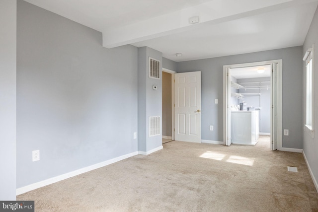 unfurnished bedroom with baseboards, visible vents, and a walk in closet