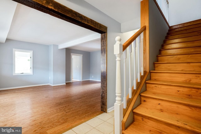 stairs with beamed ceiling, baseboards, and wood finished floors