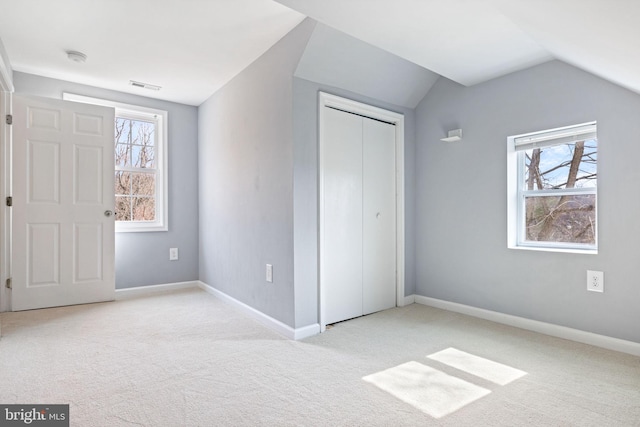 unfurnished bedroom with vaulted ceiling, multiple windows, carpet, and visible vents