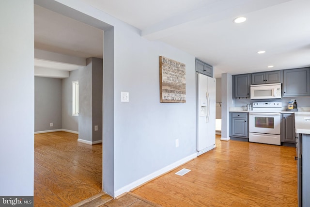 kitchen with light wood-type flooring, white appliances, visible vents, and gray cabinetry