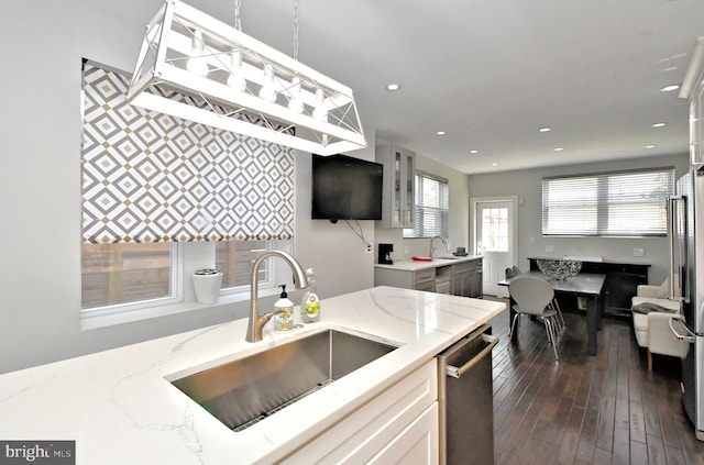 kitchen with appliances with stainless steel finishes, sink, white cabinets, dark hardwood / wood-style flooring, and light stone counters