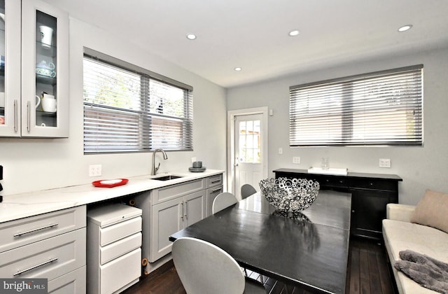 kitchen featuring light stone counters, dark hardwood / wood-style flooring, sink, and gray cabinetry