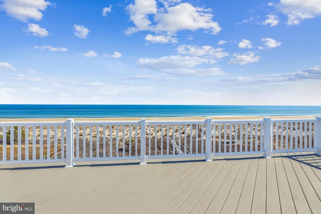 wooden deck featuring a beach view and a water view