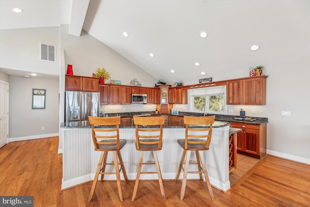 kitchen with a breakfast bar area, a kitchen island, visible vents, appliances with stainless steel finishes, and light wood-type flooring