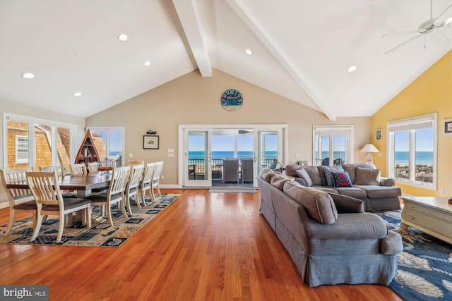 living area with beam ceiling, plenty of natural light, and light wood-style flooring