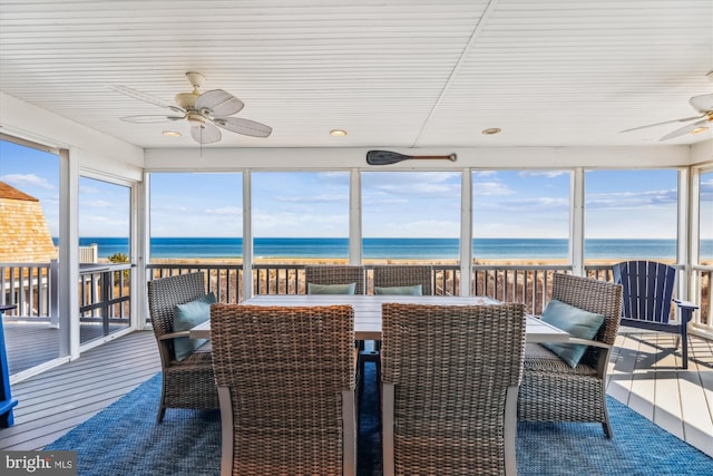 sunroom featuring ceiling fan, a water view, and a healthy amount of sunlight