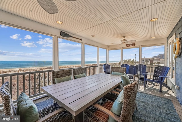 sunroom / solarium featuring ceiling fan, a water view, wooden ceiling, and a view of the beach