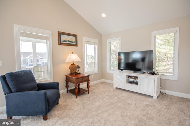 living area with light carpet, lofted ceiling, and a healthy amount of sunlight