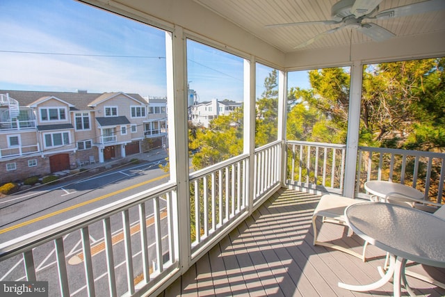 sunroom featuring ceiling fan and a residential view