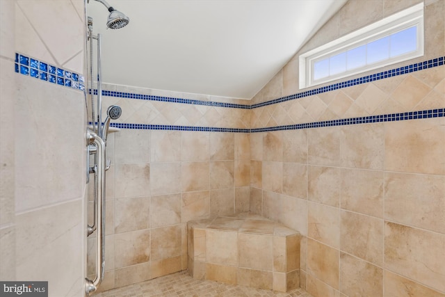 bathroom with vaulted ceiling and a tile shower