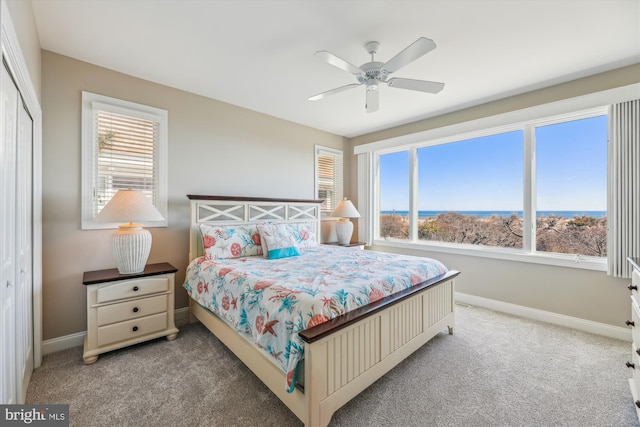 bedroom with light carpet, ceiling fan, baseboards, and a closet