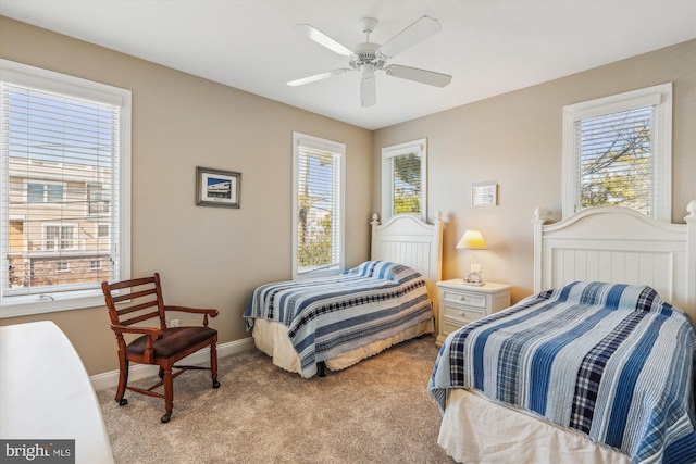 bedroom with a ceiling fan, light colored carpet, baseboards, and multiple windows