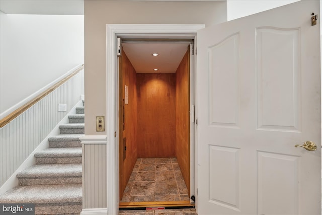 interior space featuring stone finish floor, wainscoting, and elevator