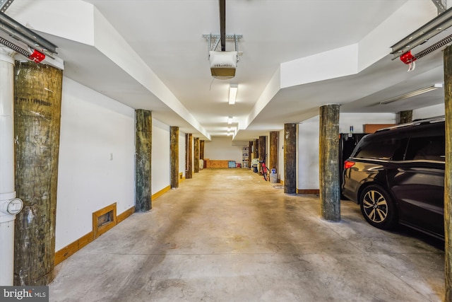 parking garage featuring a garage door opener and baseboards