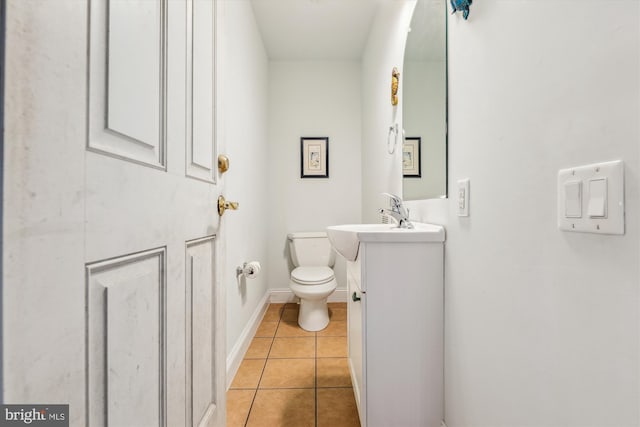 half bathroom with toilet, vanity, baseboards, and tile patterned floors