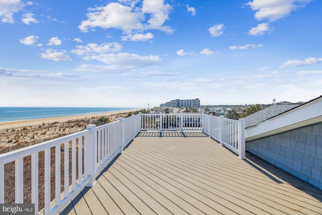 wooden deck featuring a water view and a beach view