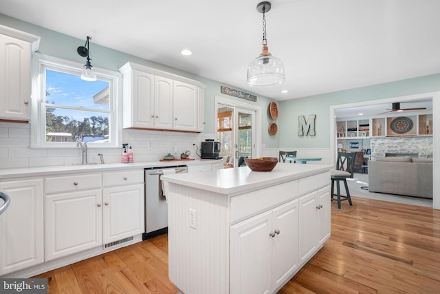 kitchen featuring a center island, visible vents, hanging light fixtures, light wood-style flooring, and stainless steel dishwasher