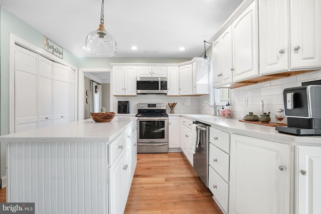 kitchen featuring appliances with stainless steel finishes, white cabinetry, light wood finished floors, and tasteful backsplash