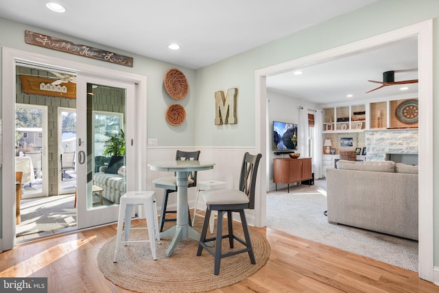 dining room with a wainscoted wall, wood finished floors, built in features, and recessed lighting