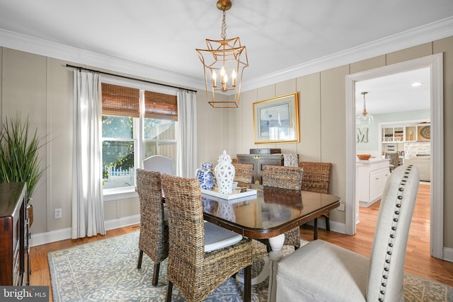 dining space with light wood finished floors, baseboards, a chandelier, and crown molding