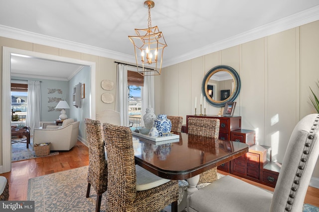 dining area featuring a chandelier, a healthy amount of sunlight, crown molding, and wood finished floors