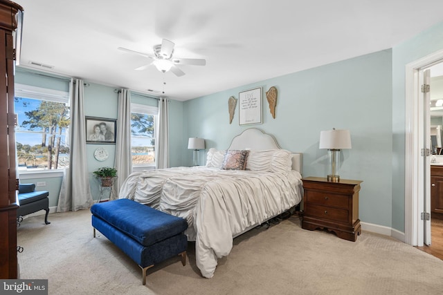 bedroom featuring carpet, visible vents, ceiling fan, ensuite bath, and baseboards