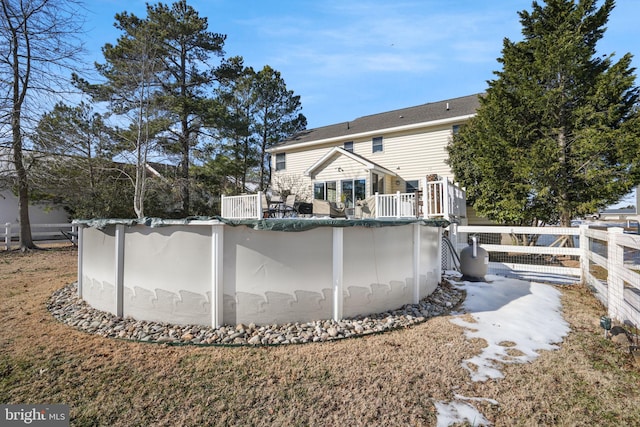 rear view of house with fence and a covered pool