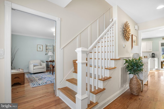 stairs with baseboards, crown molding, visible vents, and wood finished floors