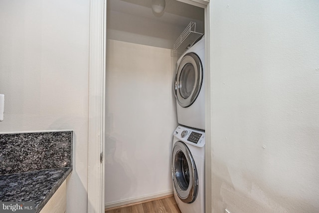 clothes washing area with light wood-type flooring, laundry area, and stacked washing maching and dryer