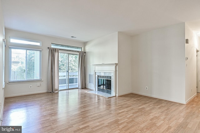 unfurnished living room featuring light wood-style floors, baseboards, and a premium fireplace