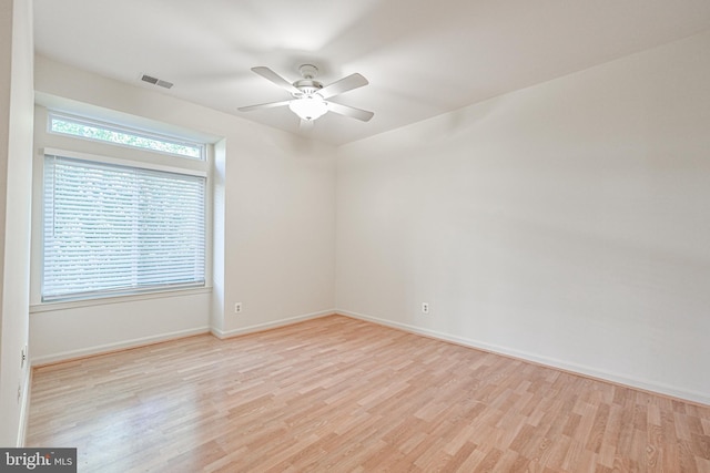 empty room with ceiling fan, light wood-type flooring, visible vents, and baseboards