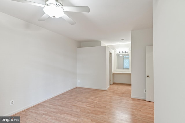 empty room with a ceiling fan, light wood-type flooring, and baseboards