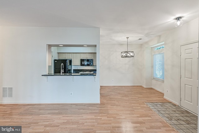 interior space featuring baseboards, light wood-type flooring, visible vents, and a notable chandelier