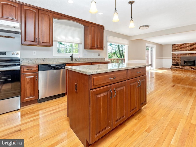 kitchen featuring a center island, hanging light fixtures, open floor plan, light wood finished floors, and appliances with stainless steel finishes