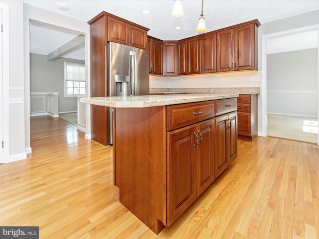 kitchen with light wood finished floors, baseboards, pendant lighting, light stone countertops, and stainless steel refrigerator with ice dispenser