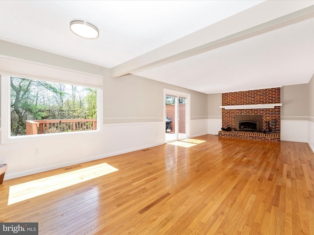 unfurnished living room with a brick fireplace, light wood finished floors, and baseboards