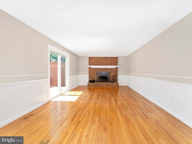 unfurnished living room featuring a fireplace, light wood-style floors, visible vents, and baseboards