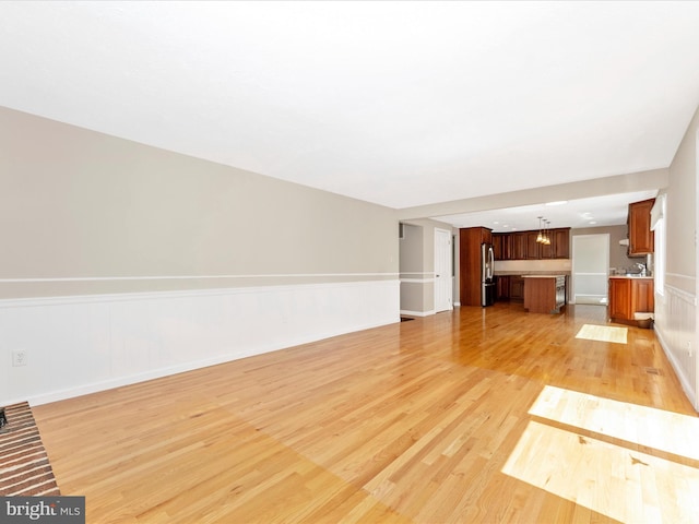 unfurnished living room with light wood finished floors and baseboards