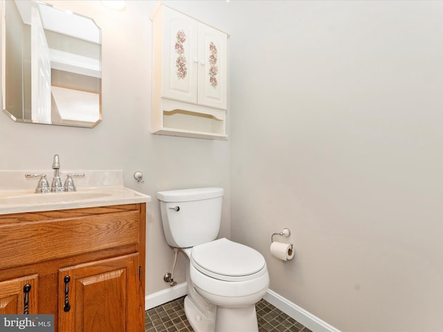 half bath featuring tile patterned flooring, baseboards, toilet, and vanity