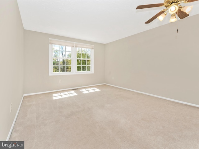 carpeted empty room with baseboards, a ceiling fan, and visible vents