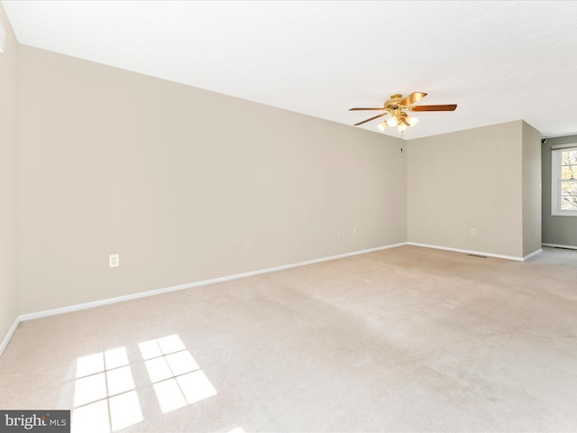 unfurnished room with visible vents, a ceiling fan, baseboards, and light carpet