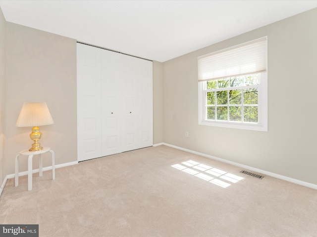 unfurnished bedroom featuring a closet, carpet floors, visible vents, and baseboards