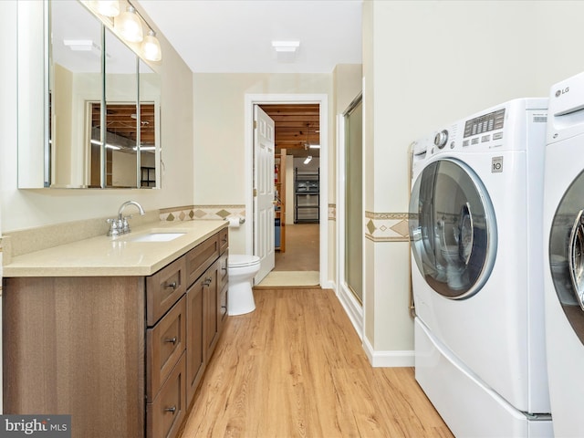 full bathroom with washer and clothes dryer, wood finished floors, a stall shower, vanity, and toilet