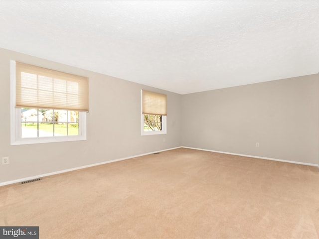 spare room featuring baseboards, visible vents, and light colored carpet