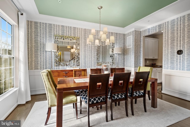 dining area featuring a wainscoted wall, a chandelier, wood finished floors, and wallpapered walls