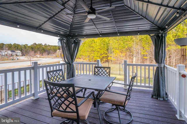 wooden deck featuring a gazebo, outdoor dining space, and a ceiling fan