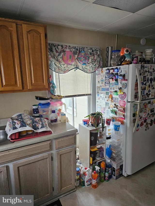 kitchen featuring brown cabinets, freestanding refrigerator, and light countertops