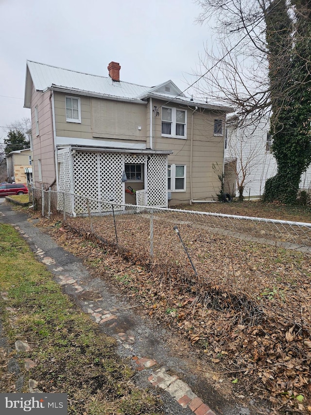 back of property with metal roof, fence, and a chimney